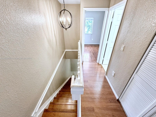 stairs featuring a chandelier and hardwood / wood-style flooring