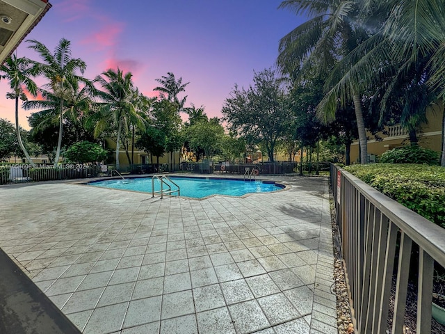 pool at dusk featuring a patio