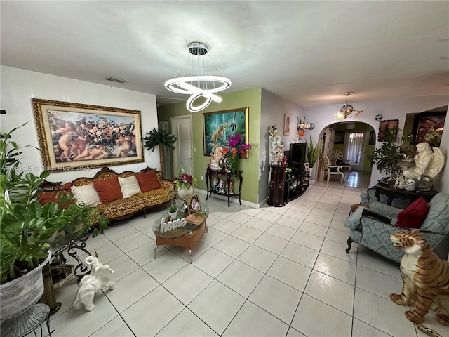 living room with arched walkways, light tile patterned floors, visible vents, an inviting chandelier, and baseboards