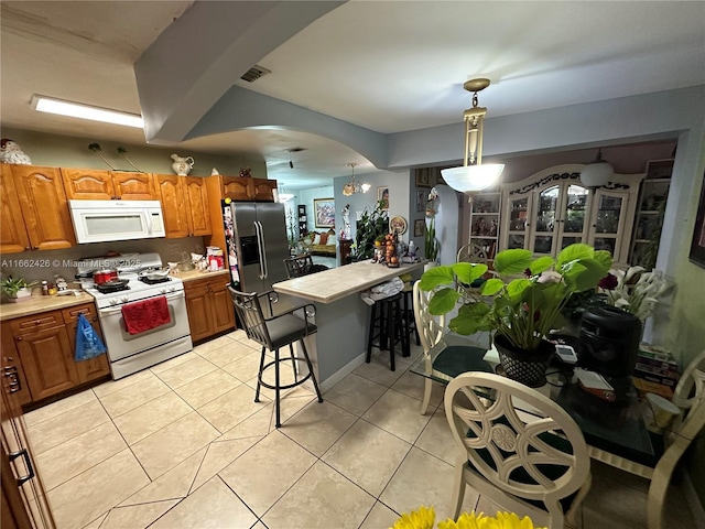 kitchen featuring light tile patterned floors, arched walkways, white appliances, visible vents, and light countertops