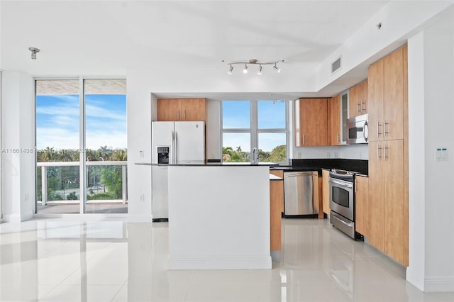 kitchen featuring light tile patterned flooring, appliances with stainless steel finishes, and a healthy amount of sunlight