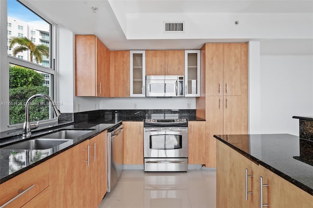 kitchen featuring appliances with stainless steel finishes, dark stone counters, and sink