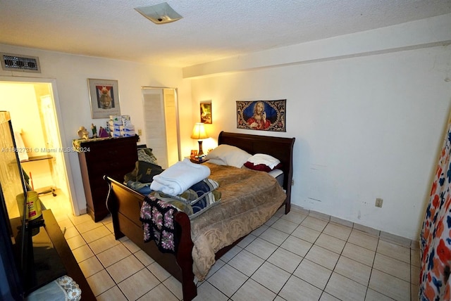 bedroom with a textured ceiling and light tile patterned floors