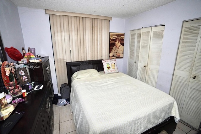 tiled bedroom featuring a textured ceiling and two closets