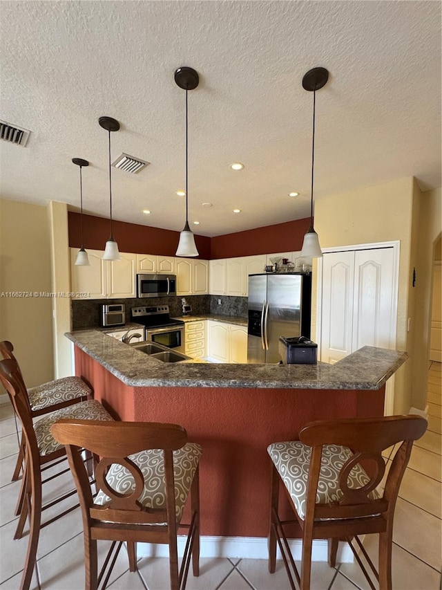 kitchen with appliances with stainless steel finishes, kitchen peninsula, a breakfast bar area, and decorative light fixtures