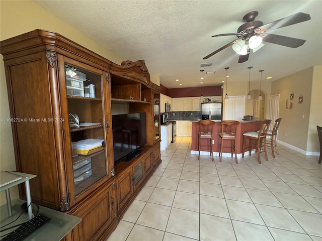 kitchen featuring ceiling fan, decorative light fixtures, appliances with stainless steel finishes, a center island, and a breakfast bar area