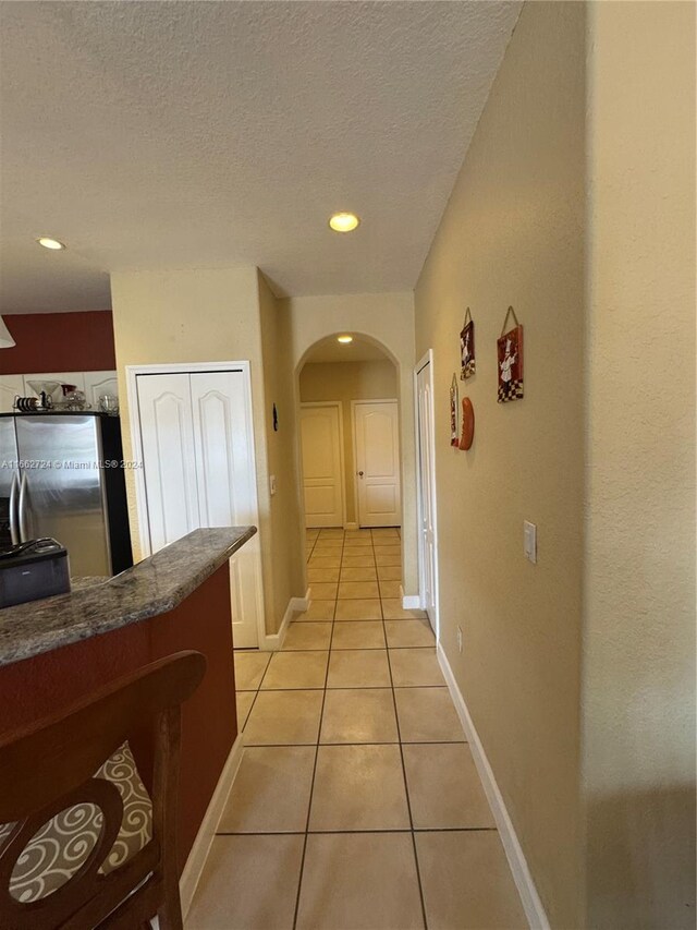 hallway featuring a textured ceiling and light tile patterned flooring