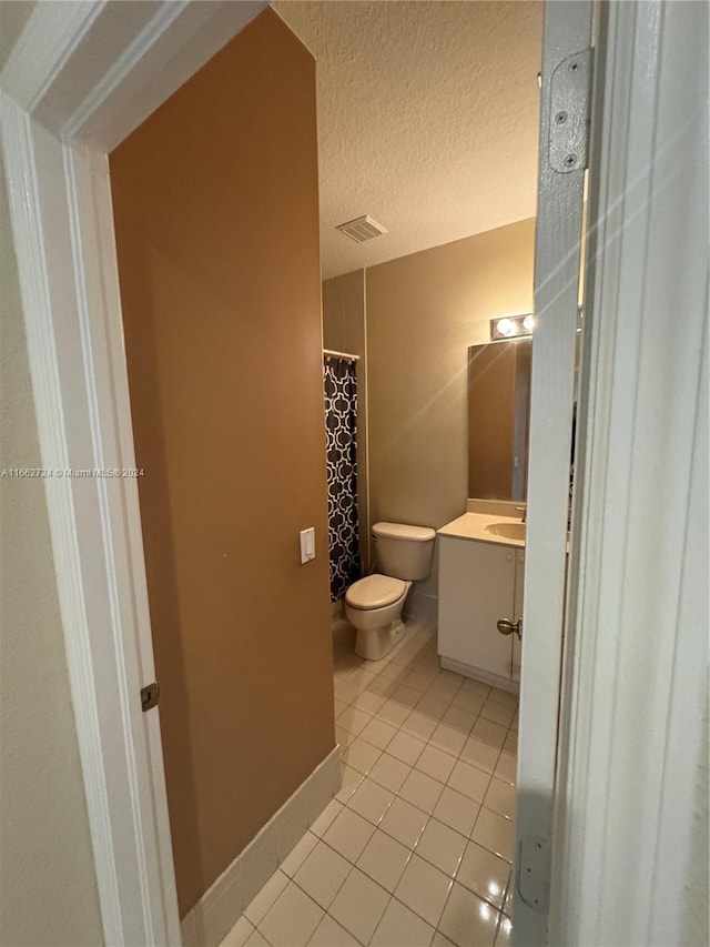 bathroom featuring tile patterned floors, a textured ceiling, vanity, and toilet