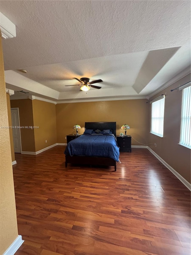 bedroom with wood-type flooring, a textured ceiling, a tray ceiling, and ceiling fan