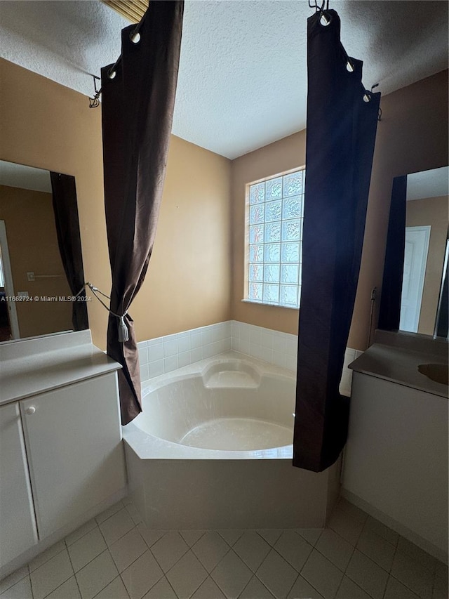 bathroom featuring tile patterned flooring, a tub to relax in, a textured ceiling, and vanity