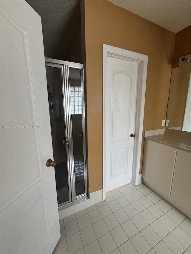 bathroom with vanity, a textured ceiling, tile patterned flooring, and an enclosed shower