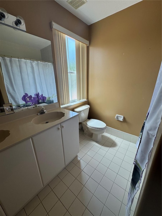 bathroom with walk in shower, vanity, toilet, and tile patterned floors