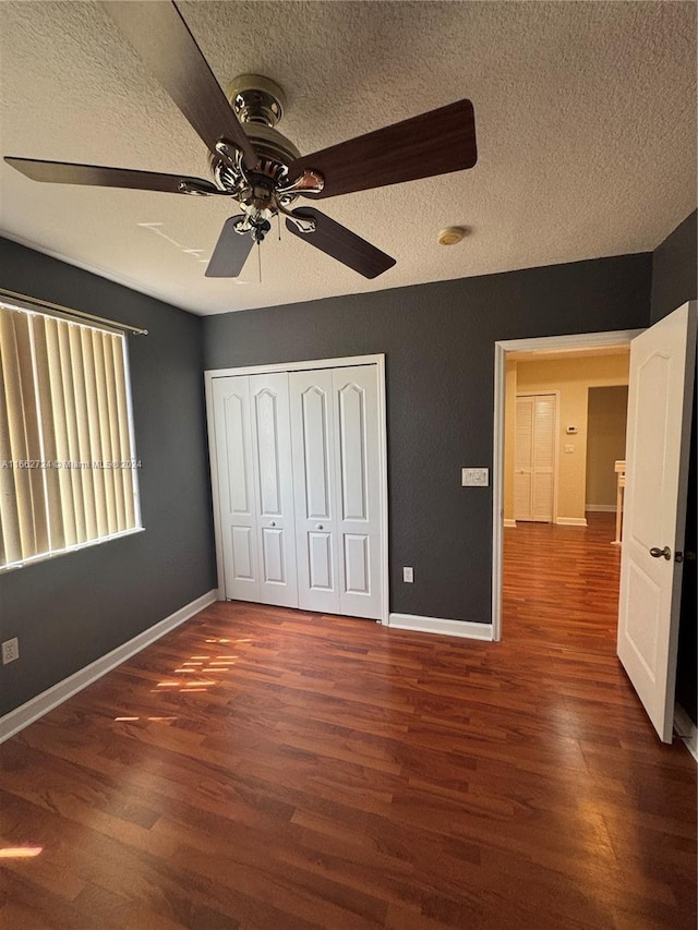 unfurnished bedroom featuring a closet, ceiling fan, dark wood-type flooring, and a textured ceiling