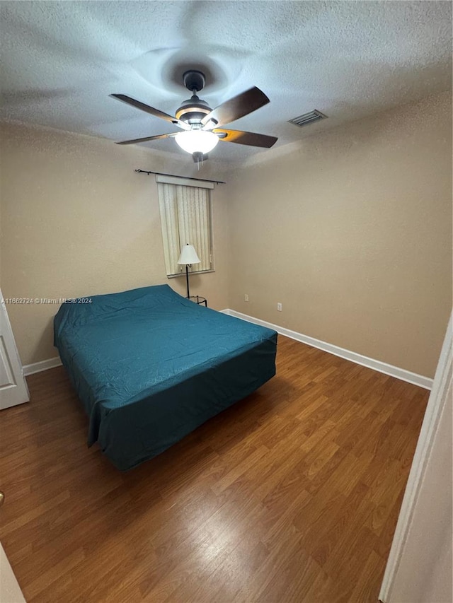 bedroom featuring a textured ceiling, wood-type flooring, and ceiling fan