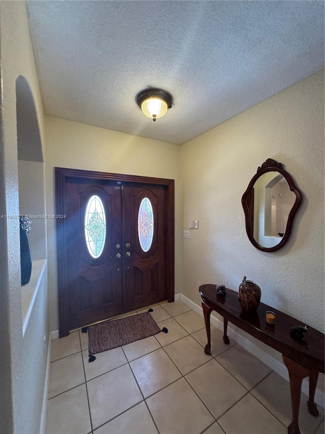 foyer with french doors, a textured ceiling, and light tile patterned flooring