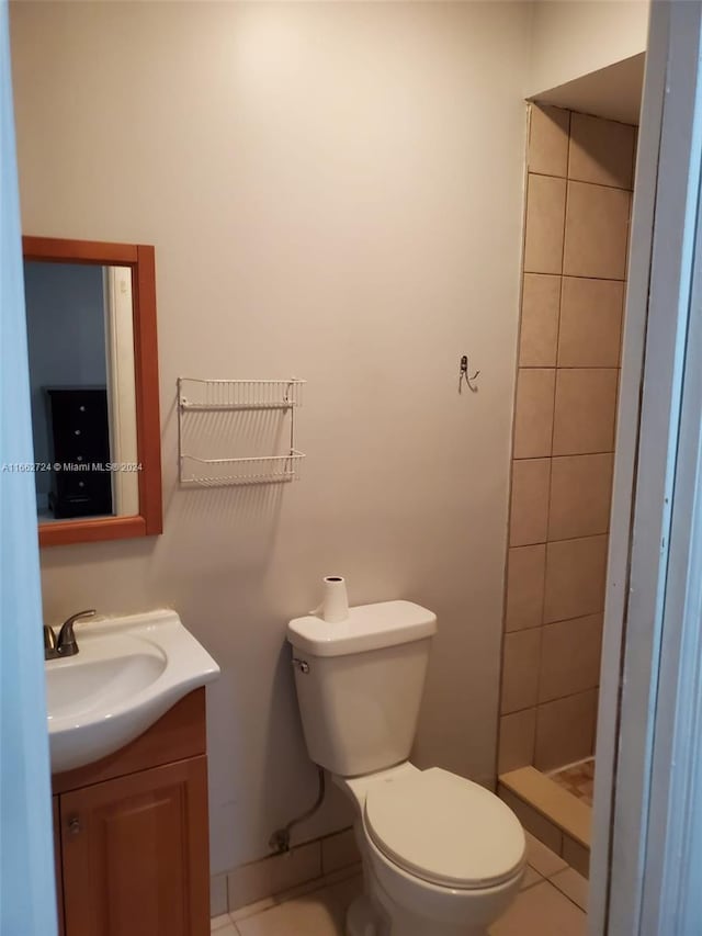 bathroom featuring tile patterned flooring, tiled shower, vanity, and toilet