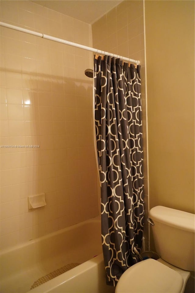 bathroom featuring toilet and shower / bath combo with shower curtain