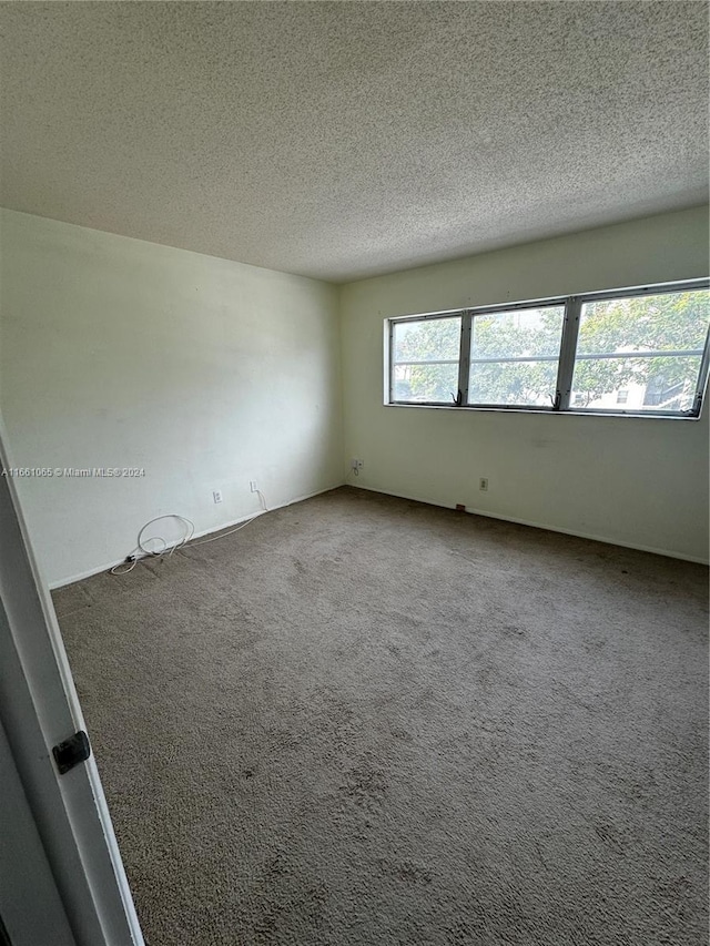 carpeted empty room featuring a textured ceiling