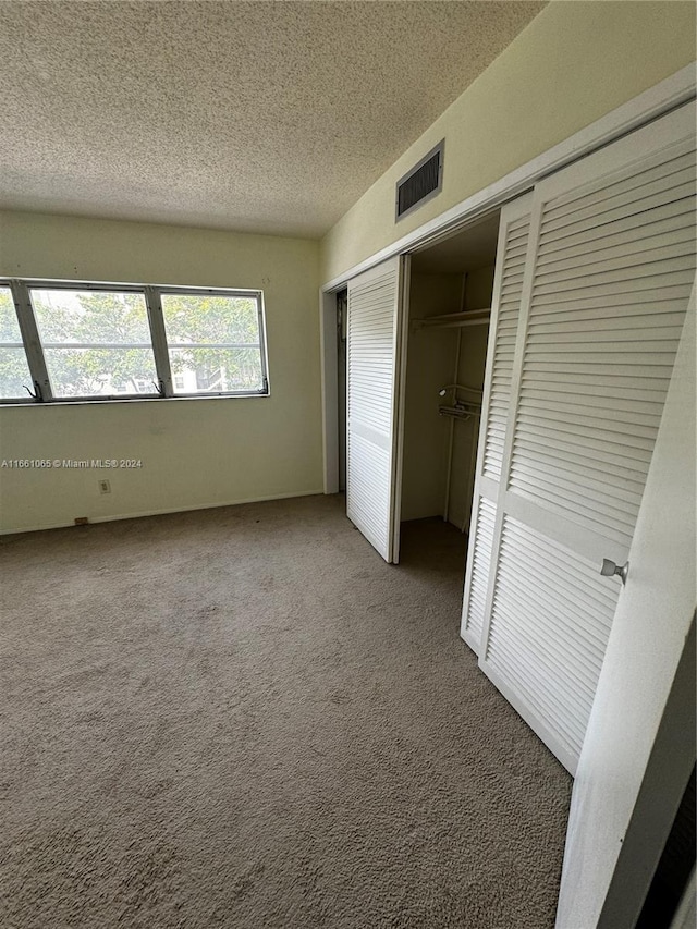 unfurnished bedroom featuring carpet floors, a textured ceiling, and a closet