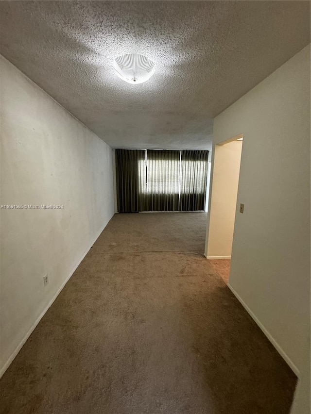 empty room with carpet and a textured ceiling