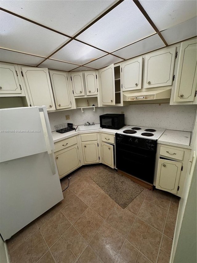 kitchen featuring dark tile patterned floors, cream cabinets, range with electric stovetop, and white fridge