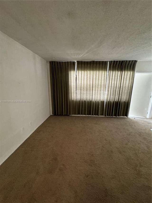 carpeted spare room with a textured ceiling