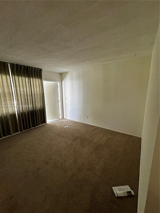 carpeted spare room featuring a textured ceiling and plenty of natural light