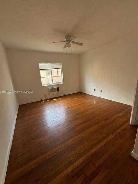 empty room with a wall mounted AC, dark wood-type flooring, and ceiling fan