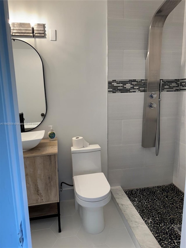 bathroom with toilet, a tile shower, vanity, and tile patterned floors