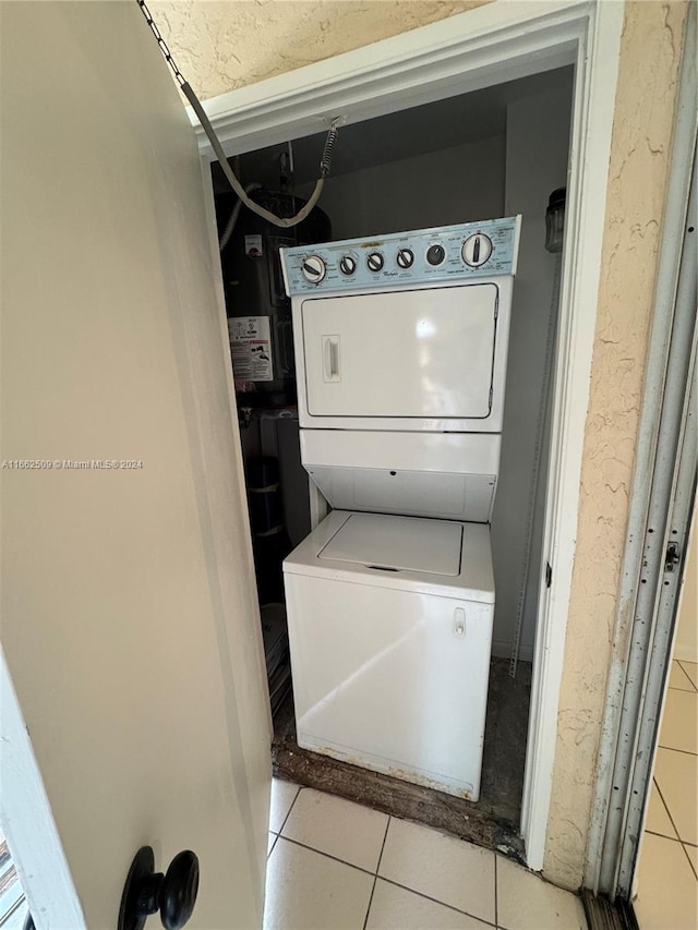 laundry room featuring stacked washing maching and dryer and light tile patterned flooring