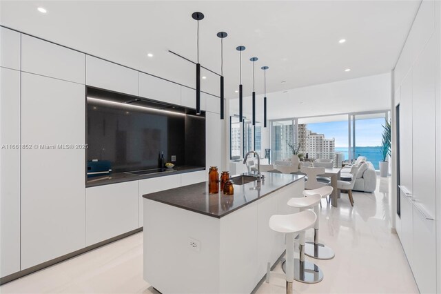 kitchen with stainless steel double oven, sink, hanging light fixtures, and white cabinets