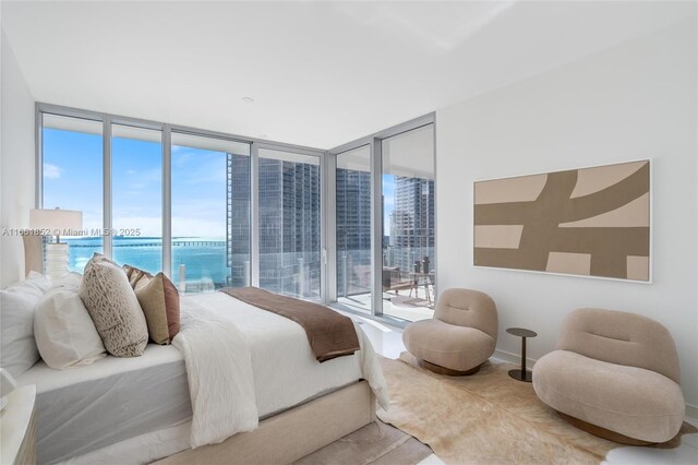 bedroom featuring a water view, expansive windows, and multiple windows