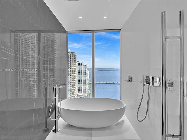 bathroom with a water view, expansive windows, and a bathing tub