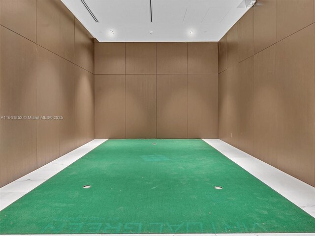 playroom with golf simulator, wooden walls, and carpet floors