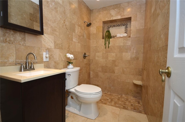 bathroom featuring tiled shower, toilet, tile walls, tile patterned flooring, and vanity