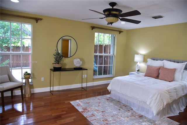 bedroom featuring dark hardwood / wood-style flooring, multiple windows, and ceiling fan