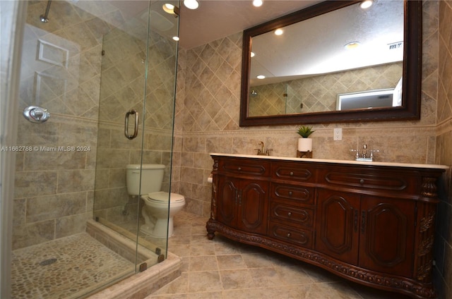 bathroom featuring tile walls, walk in shower, vanity, tile patterned flooring, and toilet