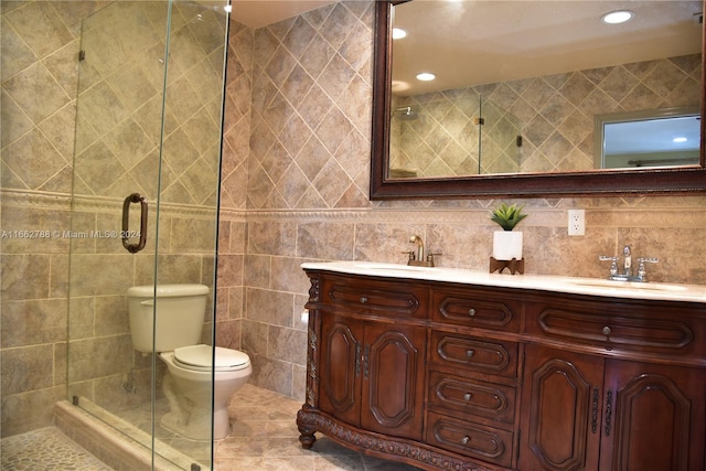 bathroom featuring vanity, a shower with shower door, tile patterned floors, toilet, and tile walls