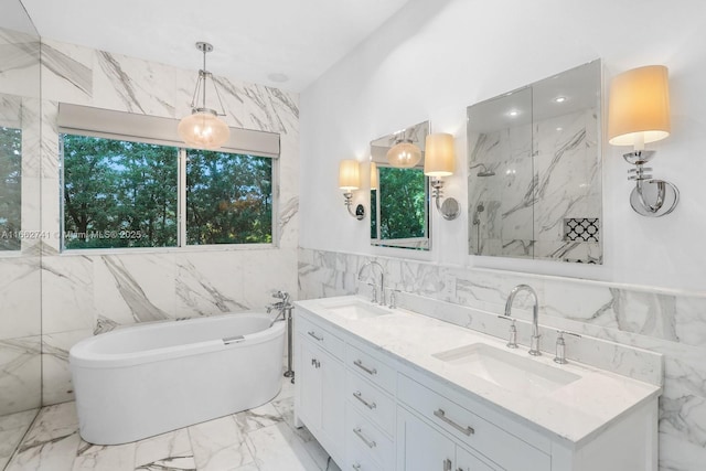 full bath featuring a freestanding bath, marble finish floor, plenty of natural light, and a sink