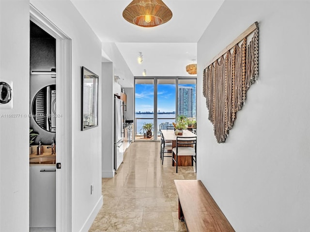 corridor featuring a water view, expansive windows, and sink