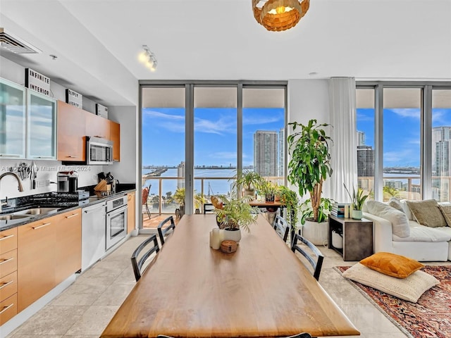 kitchen with sink, floor to ceiling windows, a water view, light brown cabinets, and light tile patterned floors