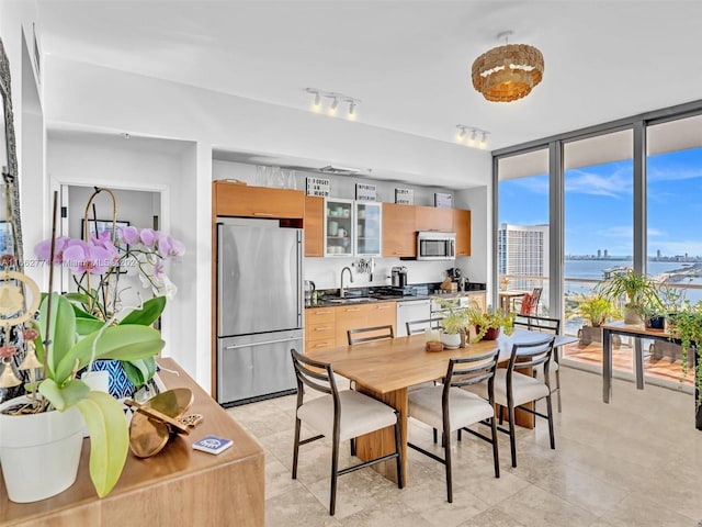 dining space with floor to ceiling windows, a water view, and sink