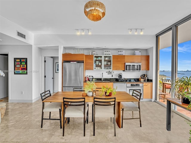 dining area featuring track lighting, sink, a water view, and expansive windows