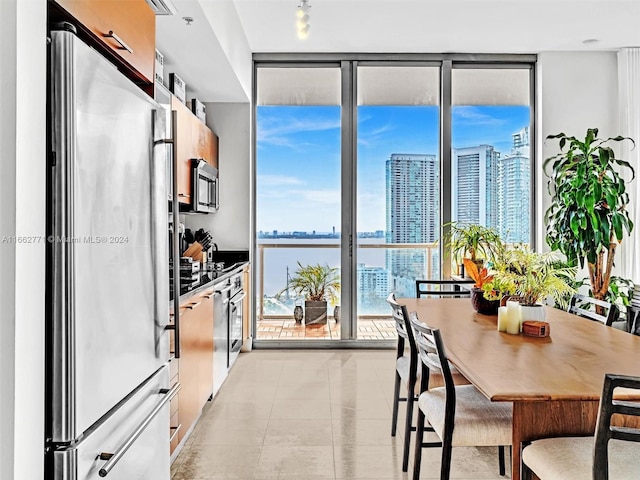 kitchen featuring a water view, light tile patterned flooring, expansive windows, and stainless steel appliances