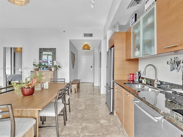 kitchen featuring dark stone countertops, stainless steel appliances, and sink