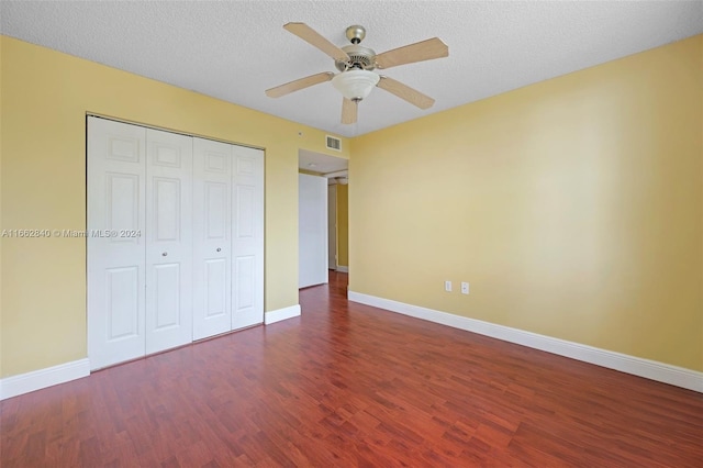 unfurnished bedroom featuring ceiling fan, a textured ceiling, a closet, and dark wood-type flooring