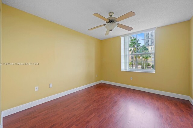 spare room featuring ceiling fan, dark wood-type flooring, and a textured ceiling