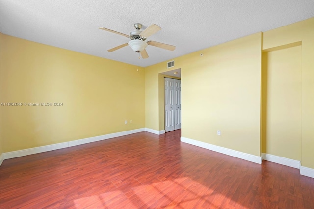 empty room featuring ceiling fan, a textured ceiling, and dark wood-type flooring