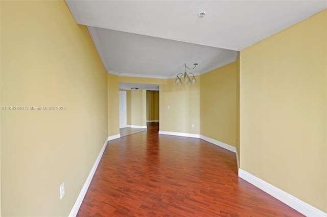 spare room with an inviting chandelier, hardwood / wood-style floors, and crown molding