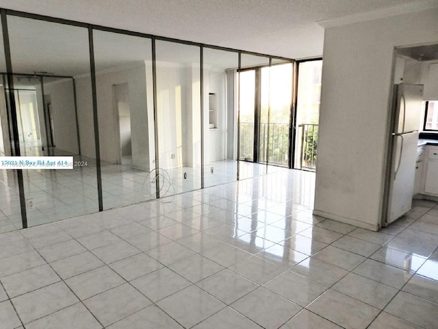 interior space featuring expansive windows, ornamental molding, a textured ceiling, and light tile patterned floors